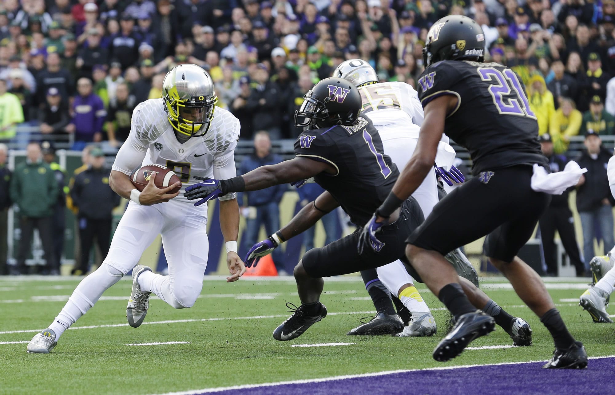 Oregon quarterback Marcus Mariota, left, runs the ball on a keeper play against Washington in the first half of an NCAA college football game, Saturday, Oct. 12, 2013, in Seattle. Mariota was stopped short of the goal line, but Oregon scored a touchdown on the next play. (AP Photo/Ted S.