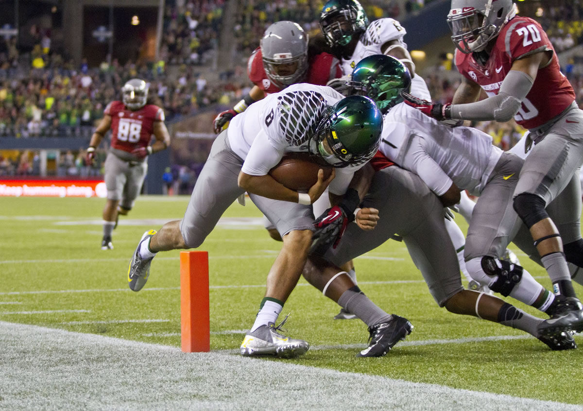 Oregon quarterback Marcus Mariota sees daylight and squeezes into the end zone with his foot barely in, scoring on a 13-yard run in a 2012 game against Washington State in Seattle.