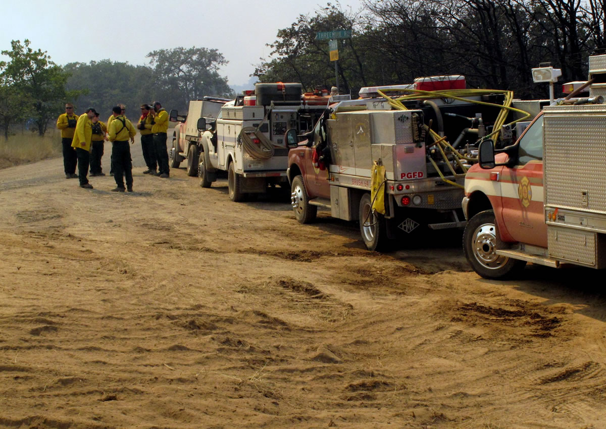 Firefighters congregate next to land charred by a wildfire burning near The Dalles, Ore., on Monday.