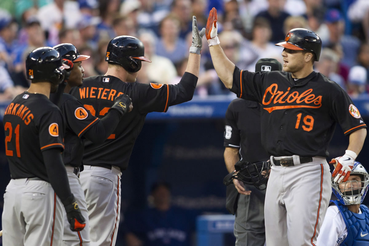Baltimore Orioles' Chris Davis, right, is congratulated by Matt Wieters, center, Adam Jones, center left,  and Nick Markakis after hitting a three-run homer as Toronto Blue Jays catcher Josh Thole looks on during the sixth inning of a baseball action in Toronto on Friday, June 21, 2013.