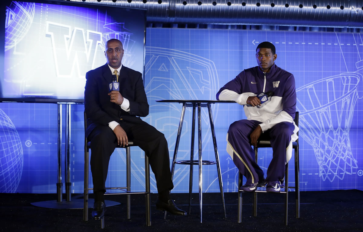 Washington head coach Lorenzo Romar, left, answers questions alongside C.J. Wilcox during the Pac-12 NCAA college basketball media day on Thursday, Oct. 17, 2013, in San Francisco.