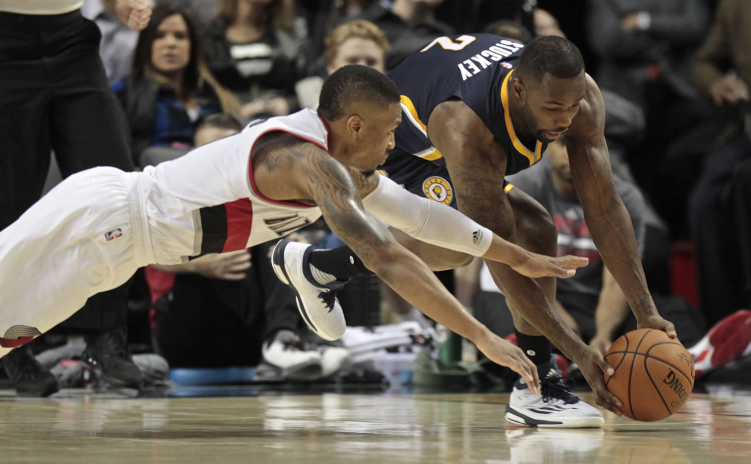 Portland Trail Blazers guard Damian Lillard (0) reaches for a loose ball against Indiana Pacers guard Rodney Stuckey (2) during the second half of an NBA basketball game in Portland, Ore., Thursday, Dec. 3, 2015. The Trail Blazers won 123-111.