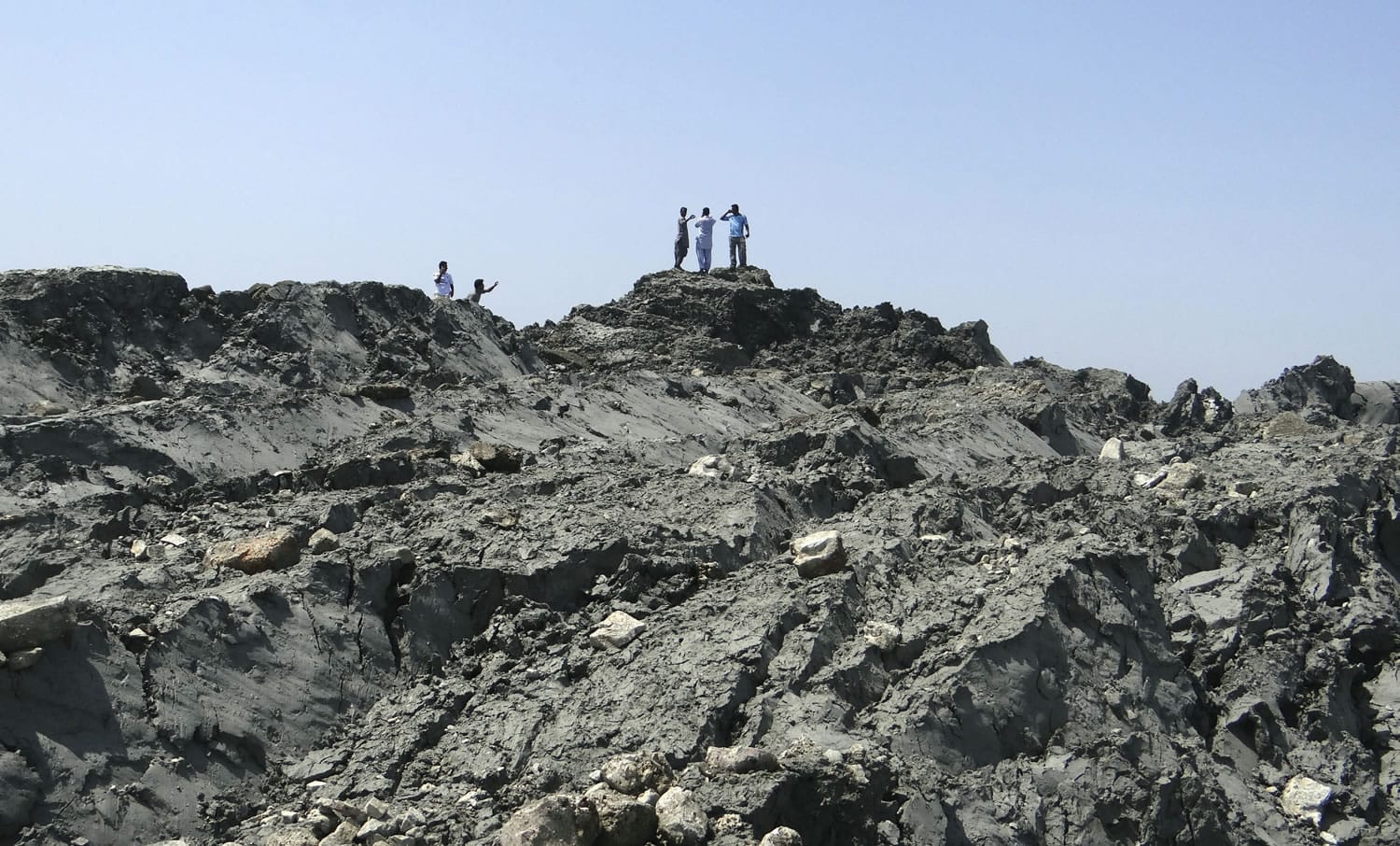 In this photo released by the Gwadar local government office on Wednesday, people walk on an island that reportedly emerged off the Gwadar coastline in the Arabian Sea.