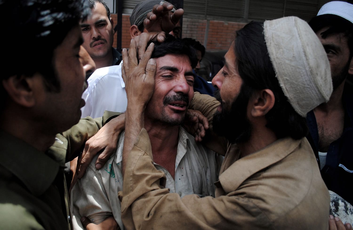 People comfort a family member of a female polio worker who was killed by unknown gunmen at a hospital in Peshawar, Pakistan, on Tuesday.