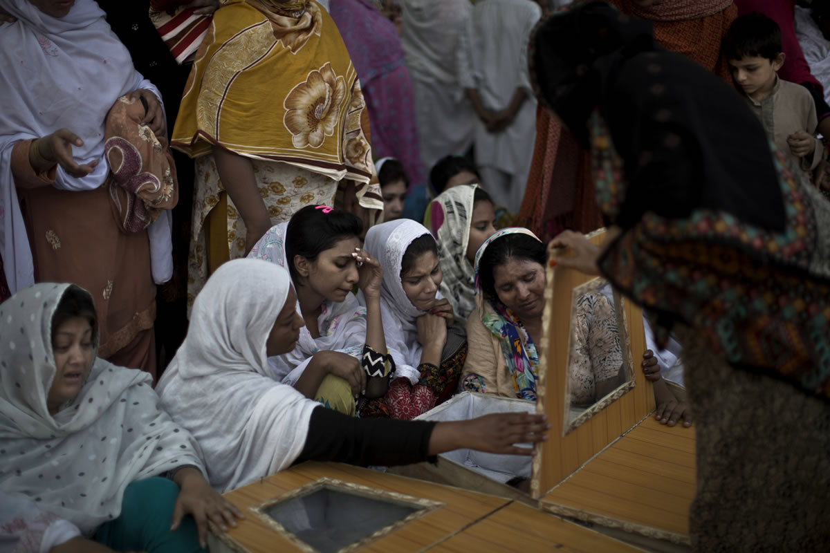 Pakistani women look inside the casket of a relative, who was killed in a suicide attack on a church in Peshawar, Pakistan on Sunday