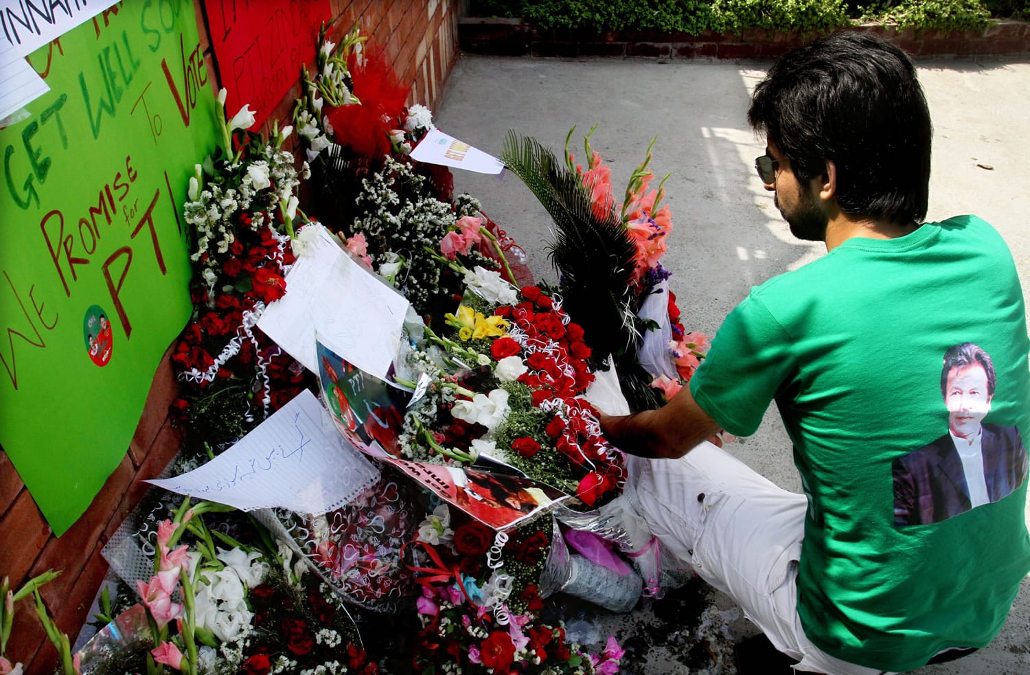 A Pakistani supporter of Imran Khan lays bouquet outside the hospital where Khan is admitted in Lahore, Pakistan, on Wednesday .