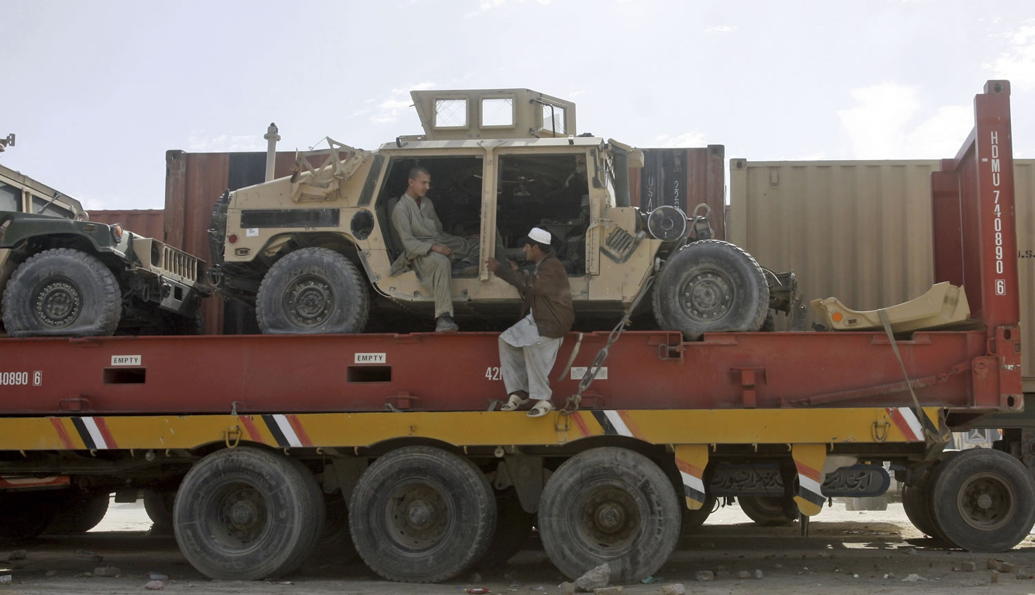Pakistani driver assistants chat while sitting on a truck carrying NATO Humvees at a terminal on the Pakistani-Afghan border in Chaman, Pakistan, Monday, Feb. 11, 2013. The U.S. says it has started using the land route through Pakistan to pull American military equipment out of Afghanistan.