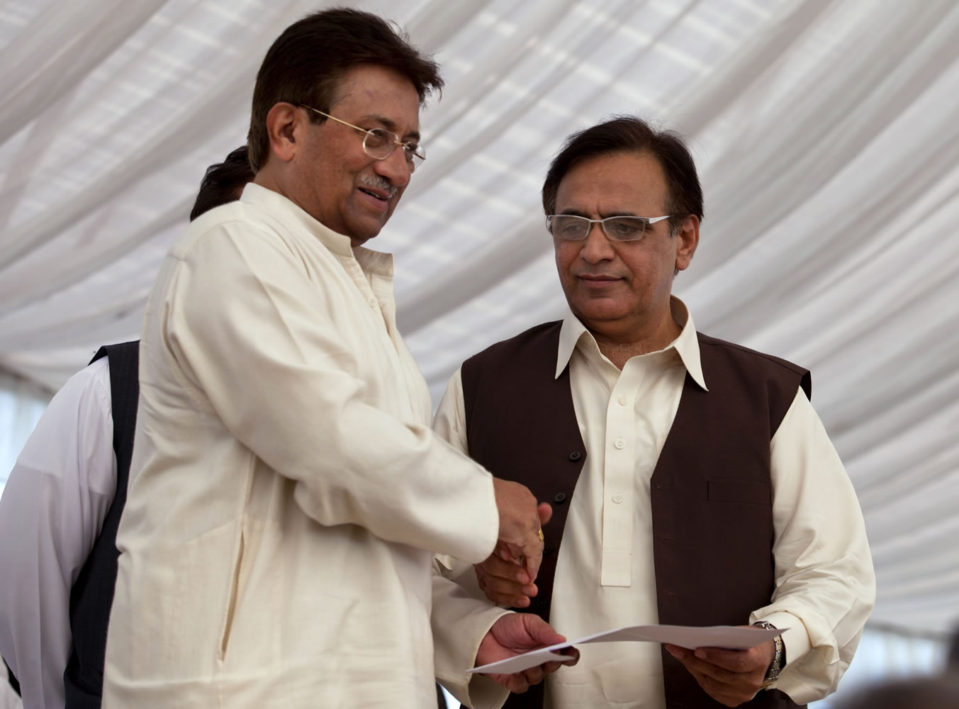 Pakistan's former President and military ruler Pervez Musharraf, left, shakes hands with Mohammad Amjad after he announces his party manifesto at his residence in Islamabad, Pakistan, on Monday.
