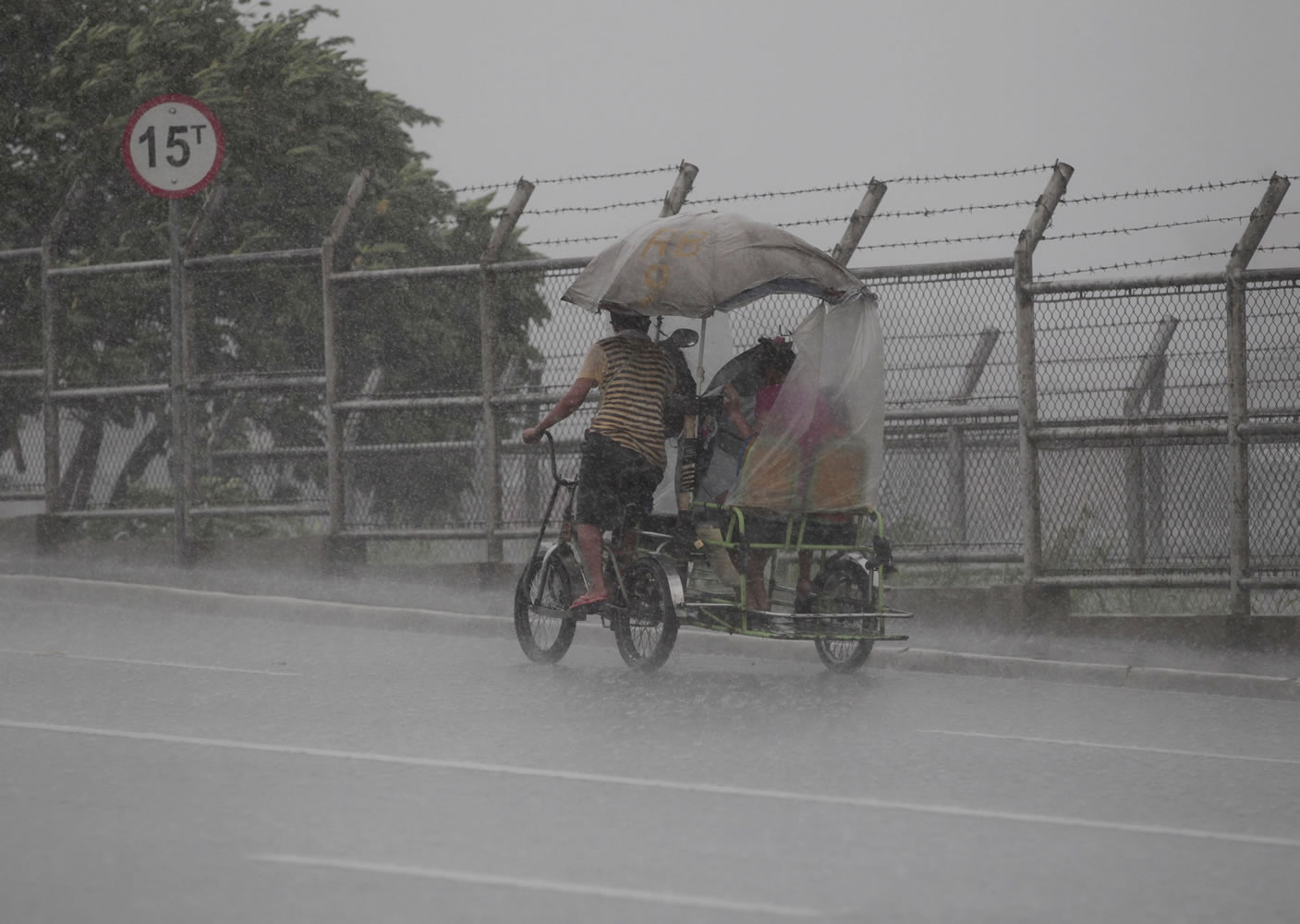 A Filipino man pedals his pedicab during a brief rainfall at Navotas, north of Manila, Philippines on Monday.