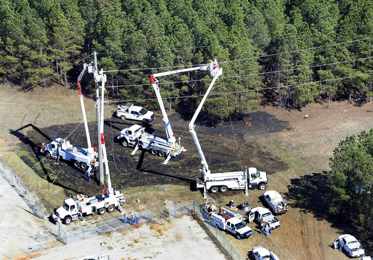 Workers from Georgia Power repair electrical lines work near the site of a private jet crash east of the Thomson-McDuffie County Airport on Thursday in Thomson, Ga. Investigators are combing the wooded area looking for clues about what led a small jet to overshoot a runway during a landing last night and crash.