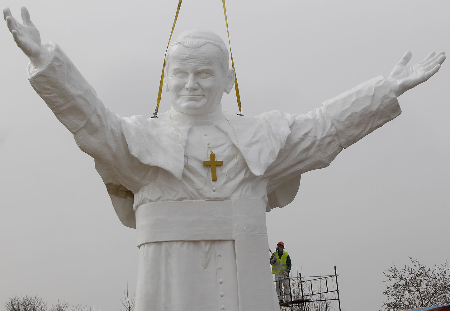 A worker adds finishing touches to a giant statue of the late Pope John Paul II.