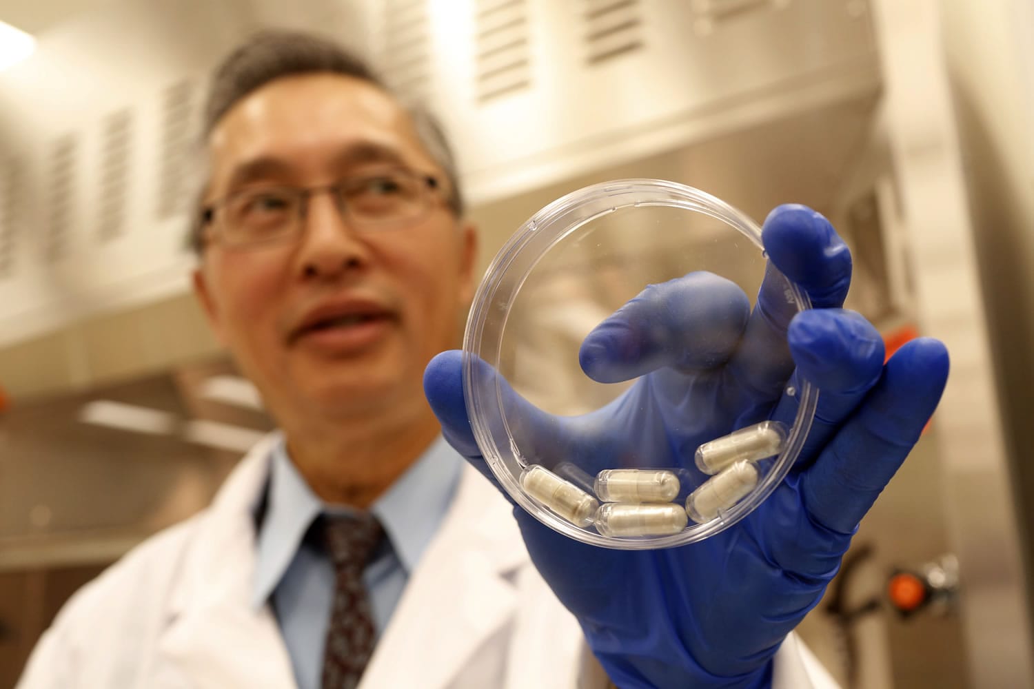 Dr. Thomas Louie, an infectious disease specialist at the University of Calgary, holds a container of stool pills in triple-coated gel capsules in his lab in Calgary, Alberta on Sept. 26.