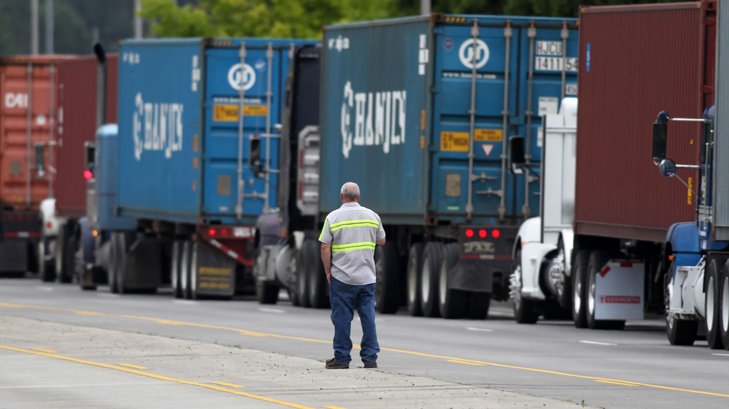 A driver looks on as container trucks line up along the highway at the Port of Portland near Terminal 6 on June 22.