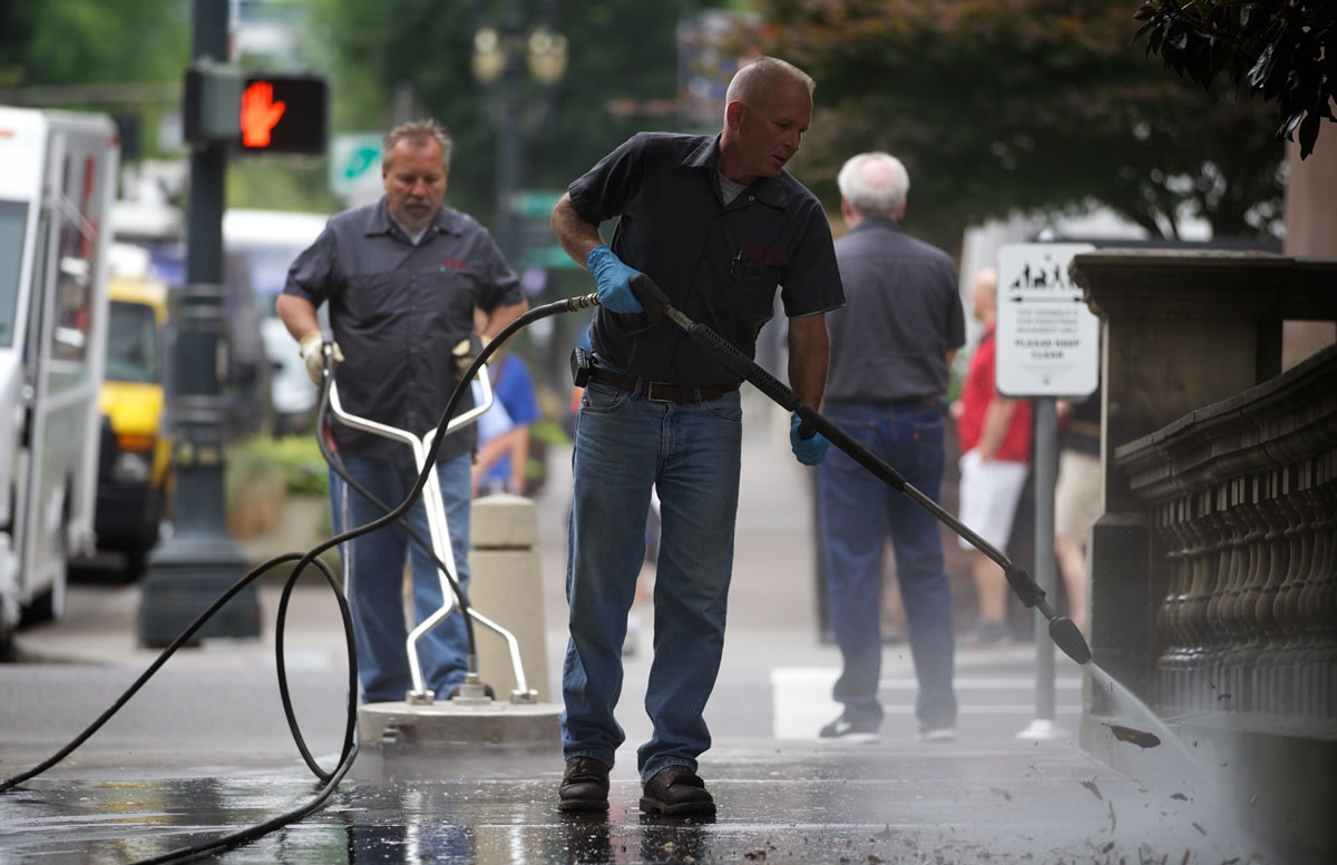 Workers with the Portland Habilitation Center clean the sidewalks in front of City Hall in Portland on Tuesday after Occupy Portland protesters were evicted.