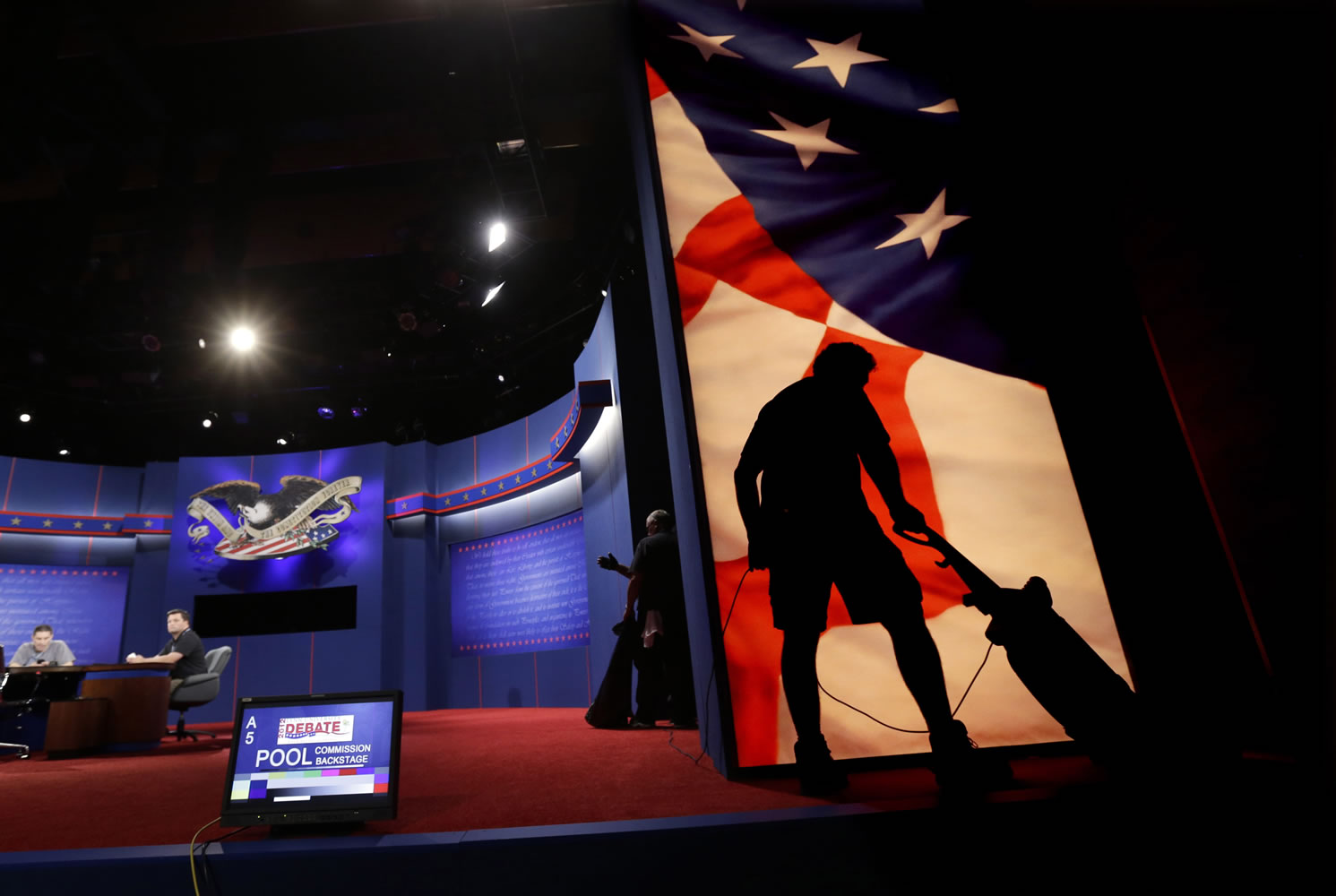 A worker vacuums as the set for tonight's presidential debate between President Barack Obama and Republican presidential candidate Mitt Romney is prepared Sunday in Boca Raton, Fla.