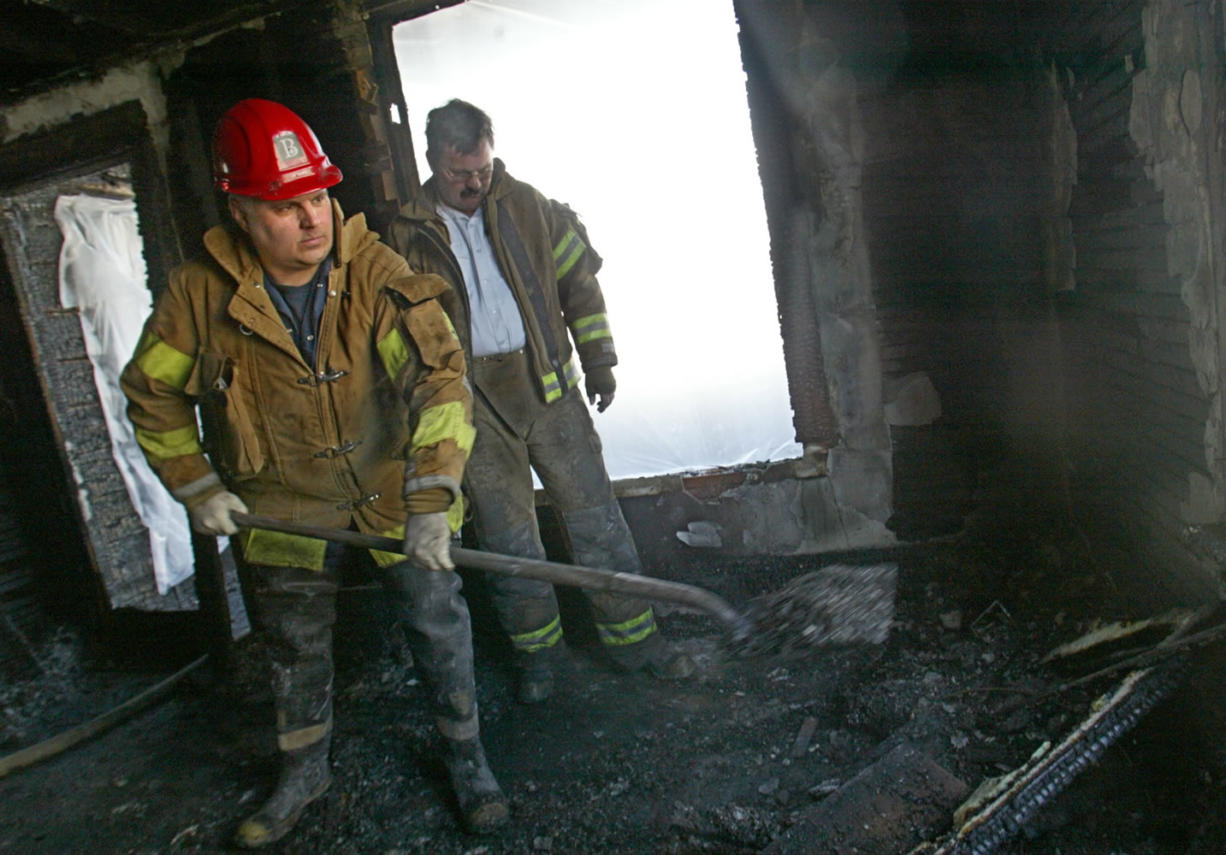 Bremerton Fire Marshal Scott Rappleye, left, and Fire Chief Al Duke sift through the charred remains of a March 2004 house fire in Bremerton. In 2009, a one-month contract clause provided a temporary pay increase of 12 percent specifically to a few long-serving lieutenants and captains. During that month, three of those workers, including Rappleye, retired.