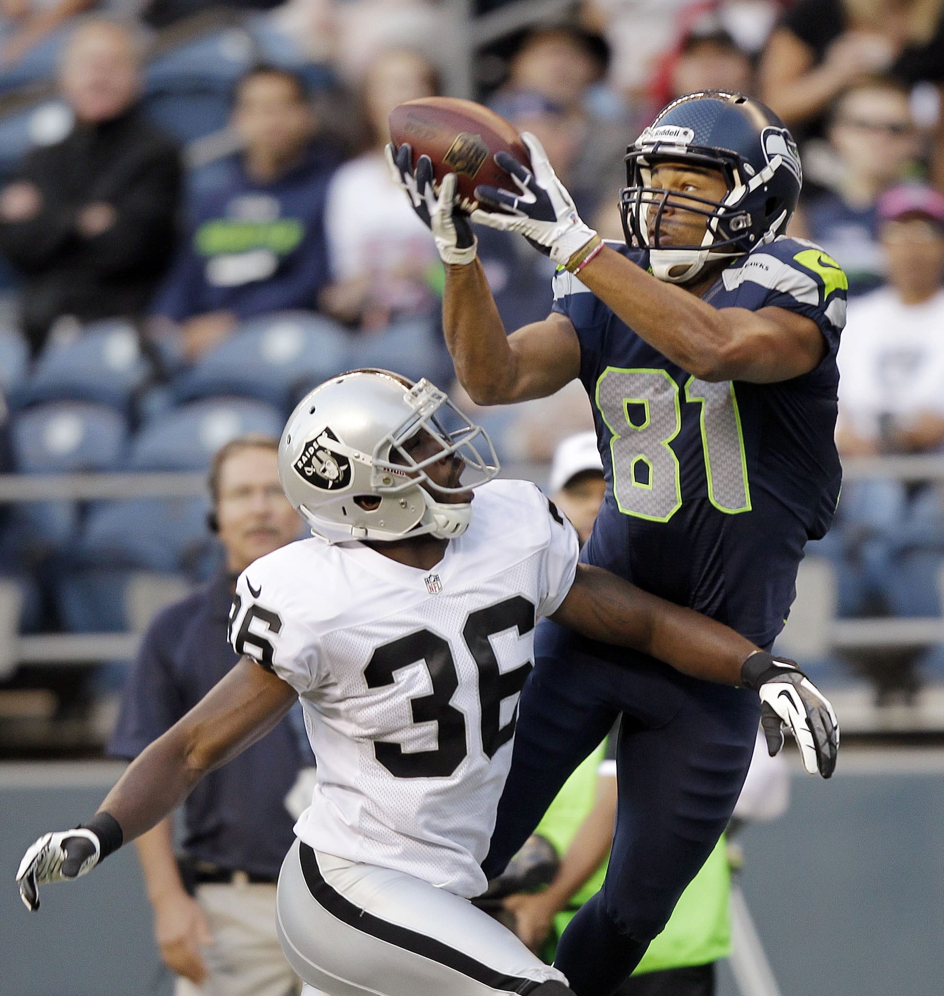 Seattle's Golden Tate (81) catches the ball in front of Oakland's Shawntae Spencer, but later left the game after being tackled on a punt return.