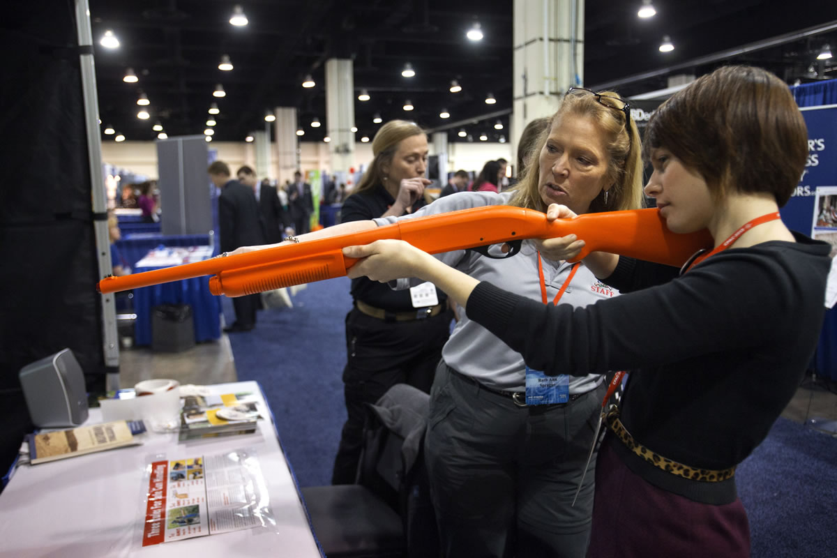 Ruthann Sprague, with the National Rifle Association, shows Bonnie Kristian, 24, of Alexandria, Va., how to hold the Laser Shot at a shooting simulator booth run by the NRA on Friday at the 40th annual Conservative Political Action Conference in National Harbor, Md.