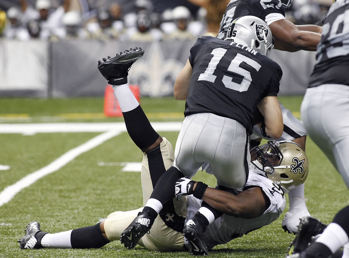 New Orleans Saints linebacker Will Smith, bottom, sacks Oakland Raiders quarterback Matt Flynn.