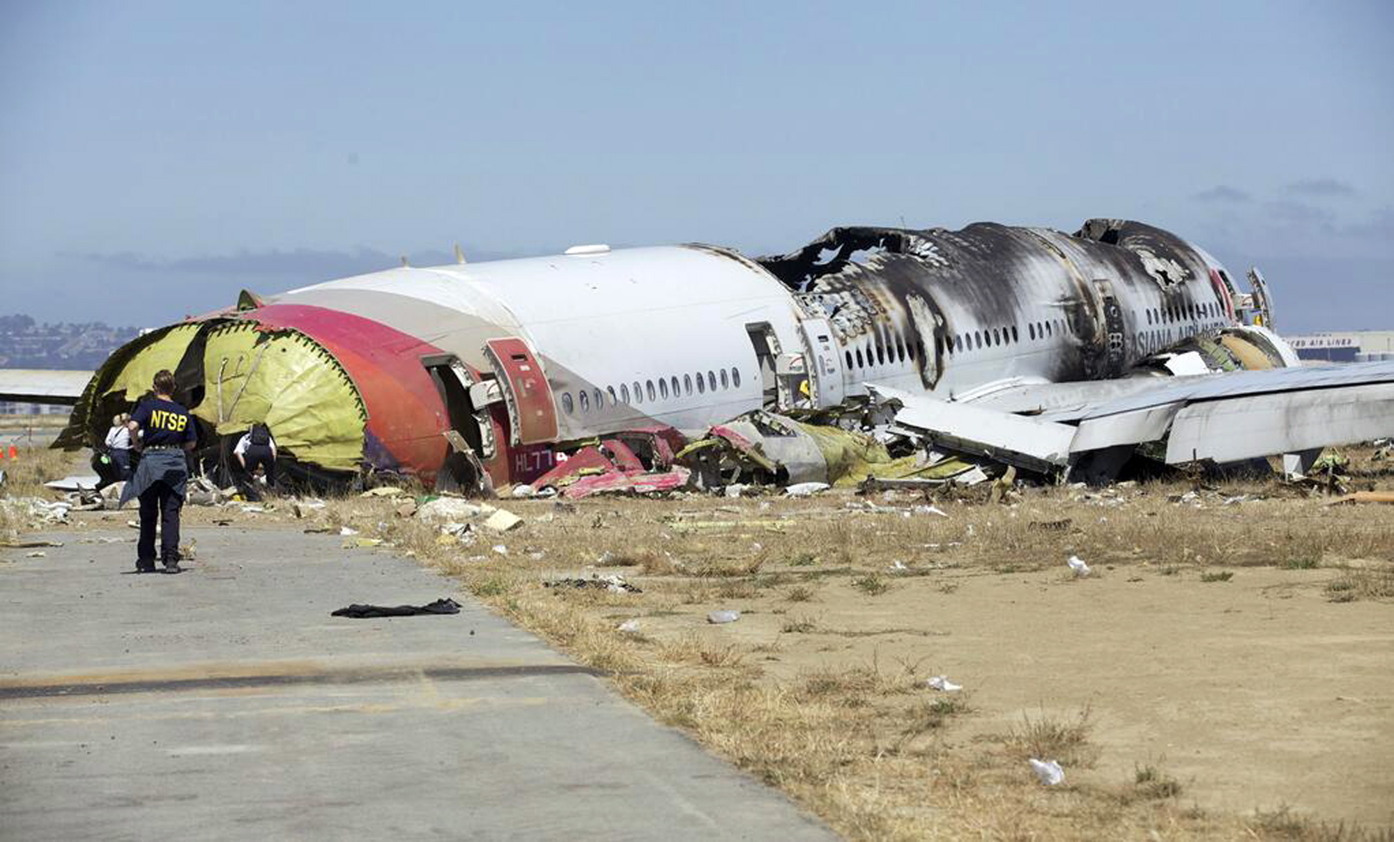 This image released by the National Transportation Safety Board Sunday, July 7, 2013, shows NTSB workers near the Boeing 777 Asiana Airlines Flight 214 aircraft. The Asiana flight crashed upon landing Saturday, July 6, at San Francisco International Airport, and two of the 307 passengers aboard were killed.