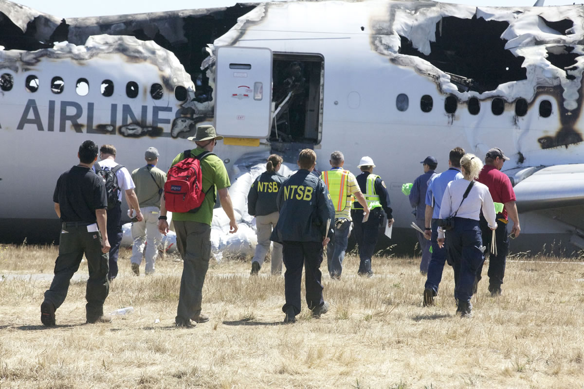 In this image provided by the NTSB, investigators examine the wreckage at the scene of the Asiana Airline crash Sunday July 7, 2013. The Asiana flight crashed upon landing Saturday, July 6, at San Francisco International Airport, and two of the 307 passengers aboard were killed.