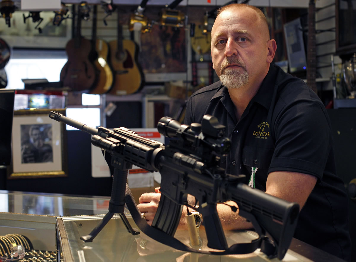Pawn shop owner Frank James poses for a picture after deciding to discontinue the selling all firearms, including a Bushmaster AR15, pictured, at his shop Loanstar Jewelry and Pawn in Seminole, Fla., on Tuesday. James says he's going to stop selling all guns and accessories in the wake of the tragedy in Connecticut.