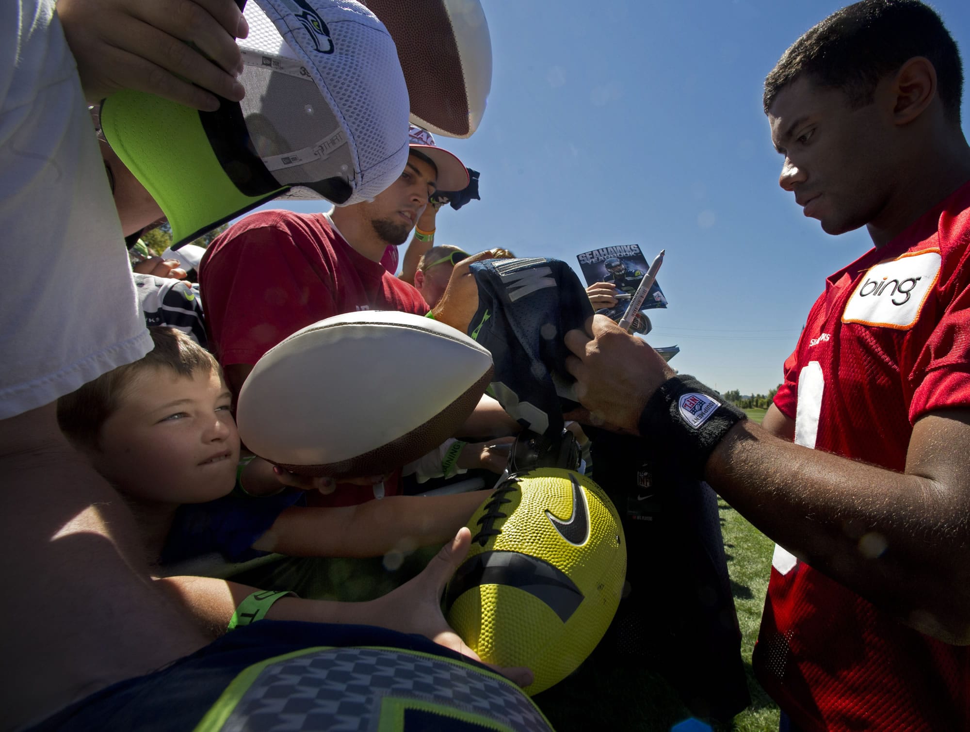 Seattle Seahawks fan Alex Eaton, 11, looks for an opening in a sea of souvenirs for an autograph for his yellow football from Seattle Seahawks quarterback Russell Wilson at training camp Friday.