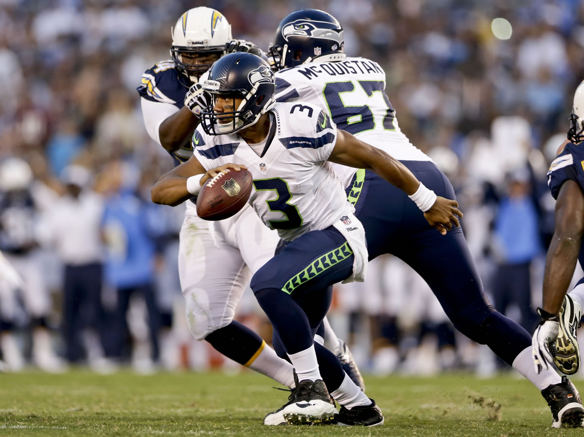 Seattle Seahawks quarterback Russell Wilson starts to scramble against the San Diego Chargers' defense in the first quarter of Thursday's NFL preseason football game in San Diego.