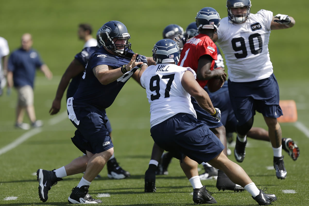Seattle Seahawks defensive tackle Jordan Hill (97) is blocked by Seahawks' Jared Smith, left, as Hill and defensive tackle Jesse Williams (90) try to get to quarterback Jerrod Johnson, second from right, during practice drills at  rookie minicamp on Friday.