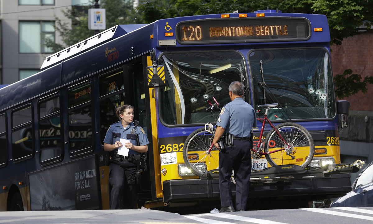 Seattle Police officers stand next to a King County Metro bus with multiple bullet holes in its windshield after a Metro bus driver was shot Monday in downtown Seattle.
