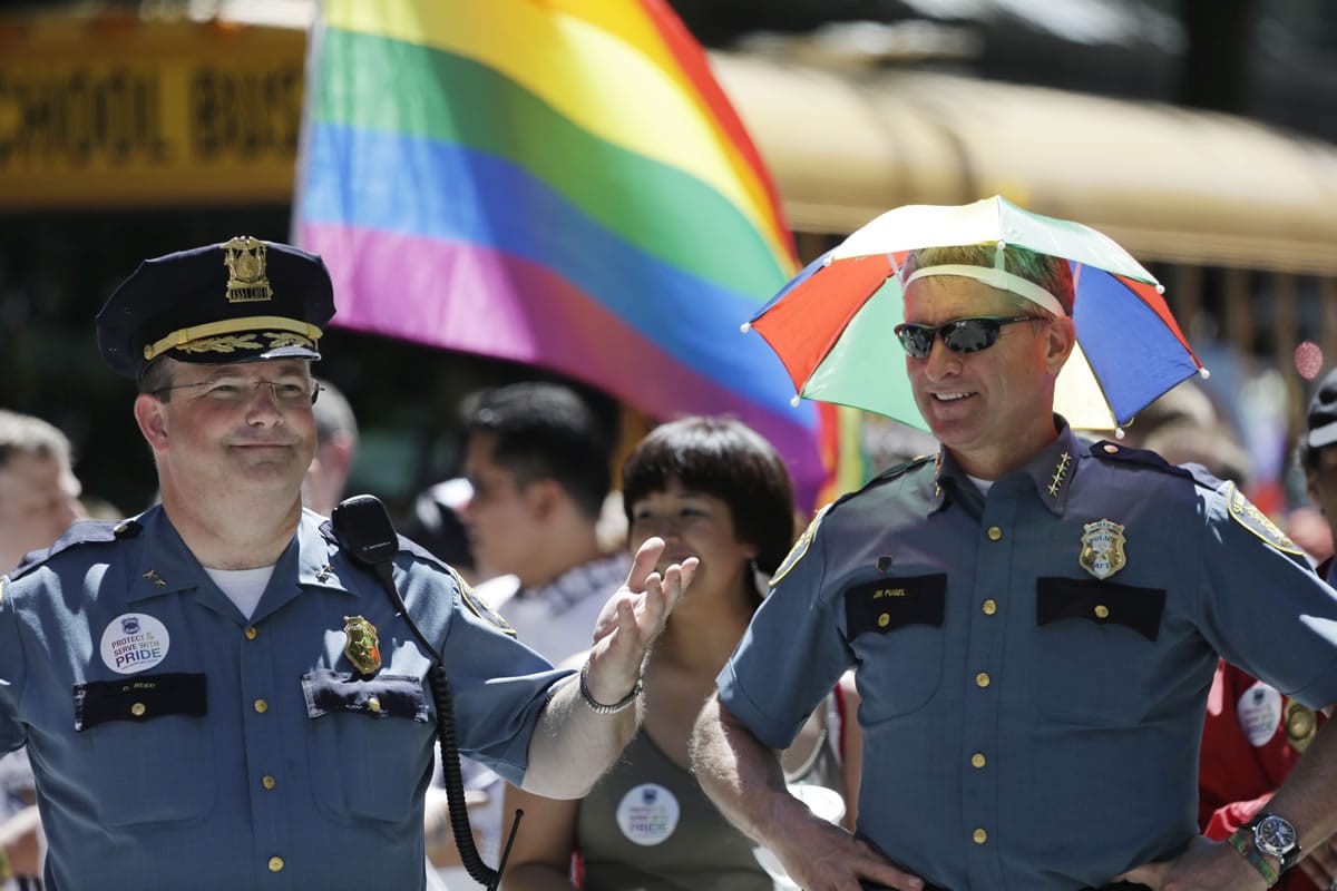 Seattle interim Police Chief Jim Pugel, right, wears a rainbow umbrella hat as he stands with Assistant Chief Dick Reed before beginning to march with other police officers in the Gay Pride parade Sunday, June 30, 2013, in Seattle.