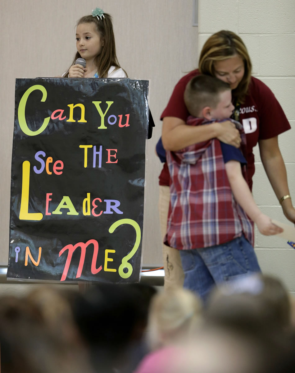Third-grader Jonathan Kent gets a hug from his teacher Mandy Brown after getting an award during a monthly leadership assembly presided over by fourth-grader Anita Bedworth at Indian Trails Elementary School in Independence, Mo.