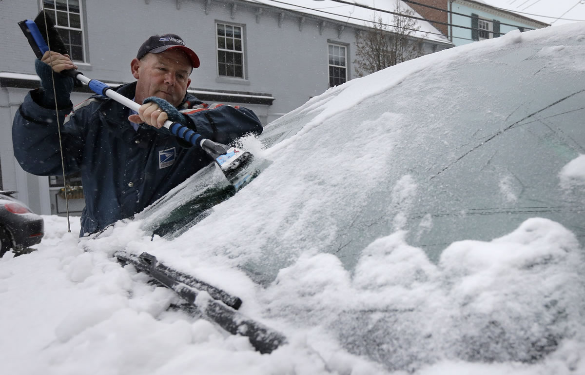 Postal worker Buddy Collins, of Eliot, Maine, scrapes ice and snow from his windshield Tuesday in Portsmouth, N.H. Highway speeds were limited in New Hampshire, where more snow is expected.