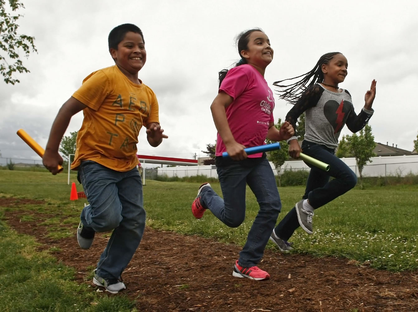 Fourth-graders, from left, Adolfo Dominguez, Lizbeth Gonzalez and Dimiah Bell practice with Hallman Elementary School's relay team in Keizer, Ore. Many of the runners received shoes from the One Thousand Soles drive.
