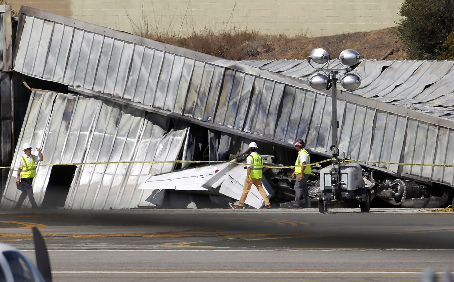 National Transportation Safety Board investigators walk by the tail of a private jet that crashed into a hangar at the Santa Monica Municipal Airport in California, as they await the arrival of a crane to access the plane. As a result of the Oct. 1 federal government partial shutdown, almost all of the board's 400 employees were furloughed, an NTSB spokeswoman said. Across America the government's work is piling up, and it's not just paperwork.