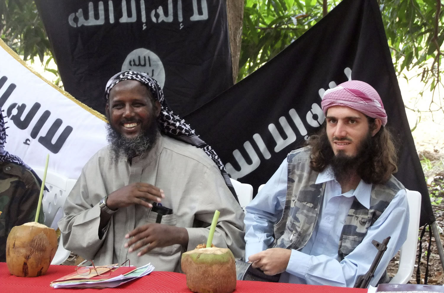 American-born Islamist militant Omar Hammami, right, and deputy leader of al-Shabab Sheik Mukhtar Abu Mansur Robow sit under a banner which reads &quot;Allah is Great&quot; during a news conference of the militant group at a farm in southern Mogadishu's Afgoye district in Somalia on May 11, 2011.