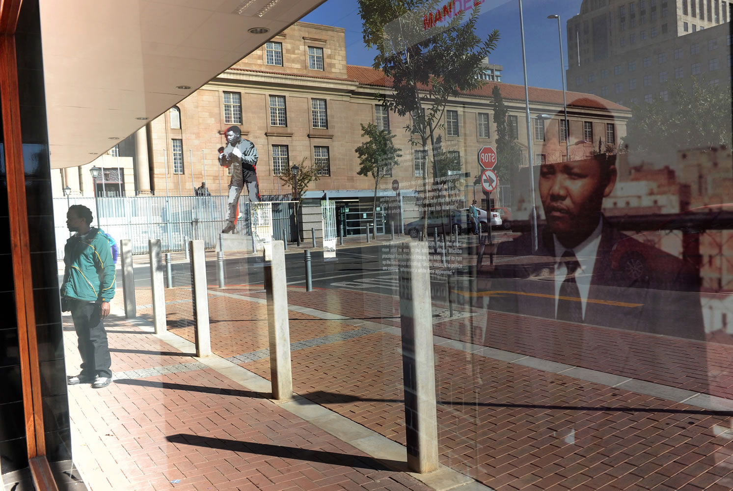 A reflected portrait and a sculpture of former president Nelson Mandela on display at Chancellor House, Mandela's offices when he practiced law in the 1950s, opposite the magistrates courts, background, in downtown Johannesburg on Tuesday.