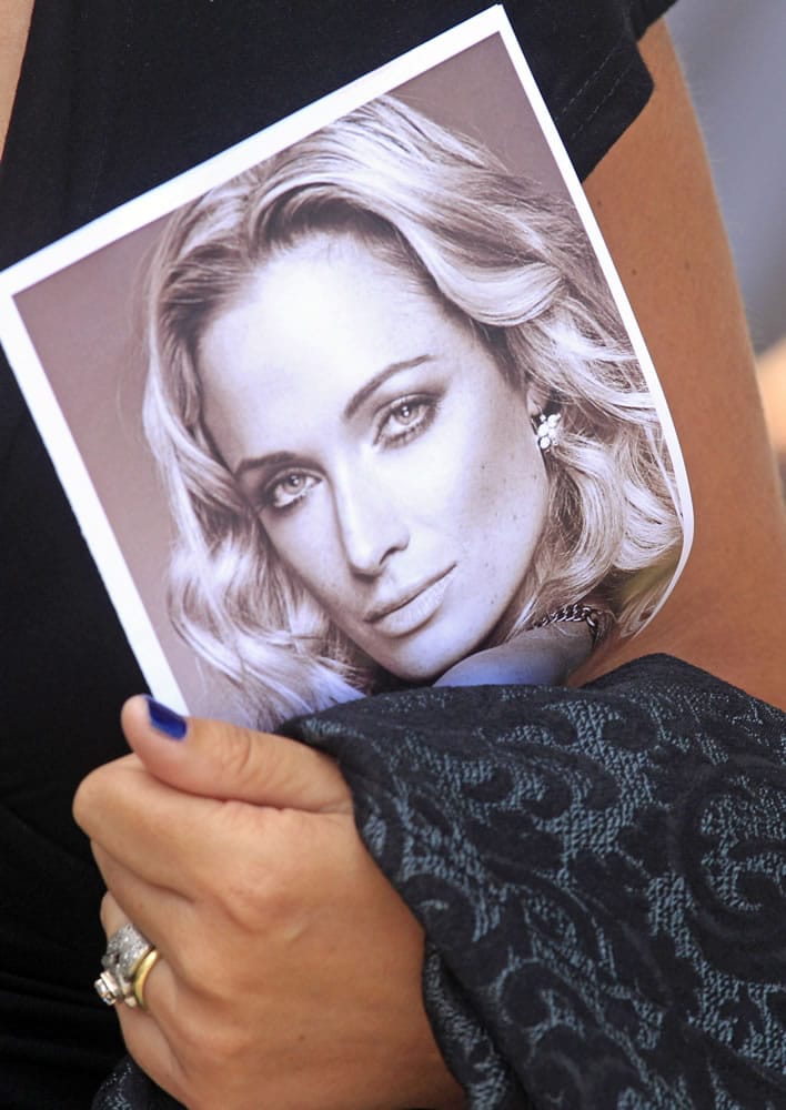 A woman holds a photo of Reeva Steenkamp, as she leaves her funeral in Port Elizabeth, South Africa, on Tuesday. Olympic athlete Oscar Pistorius is charged with the premeditated murder of Steenkamp on Valentine's Day.