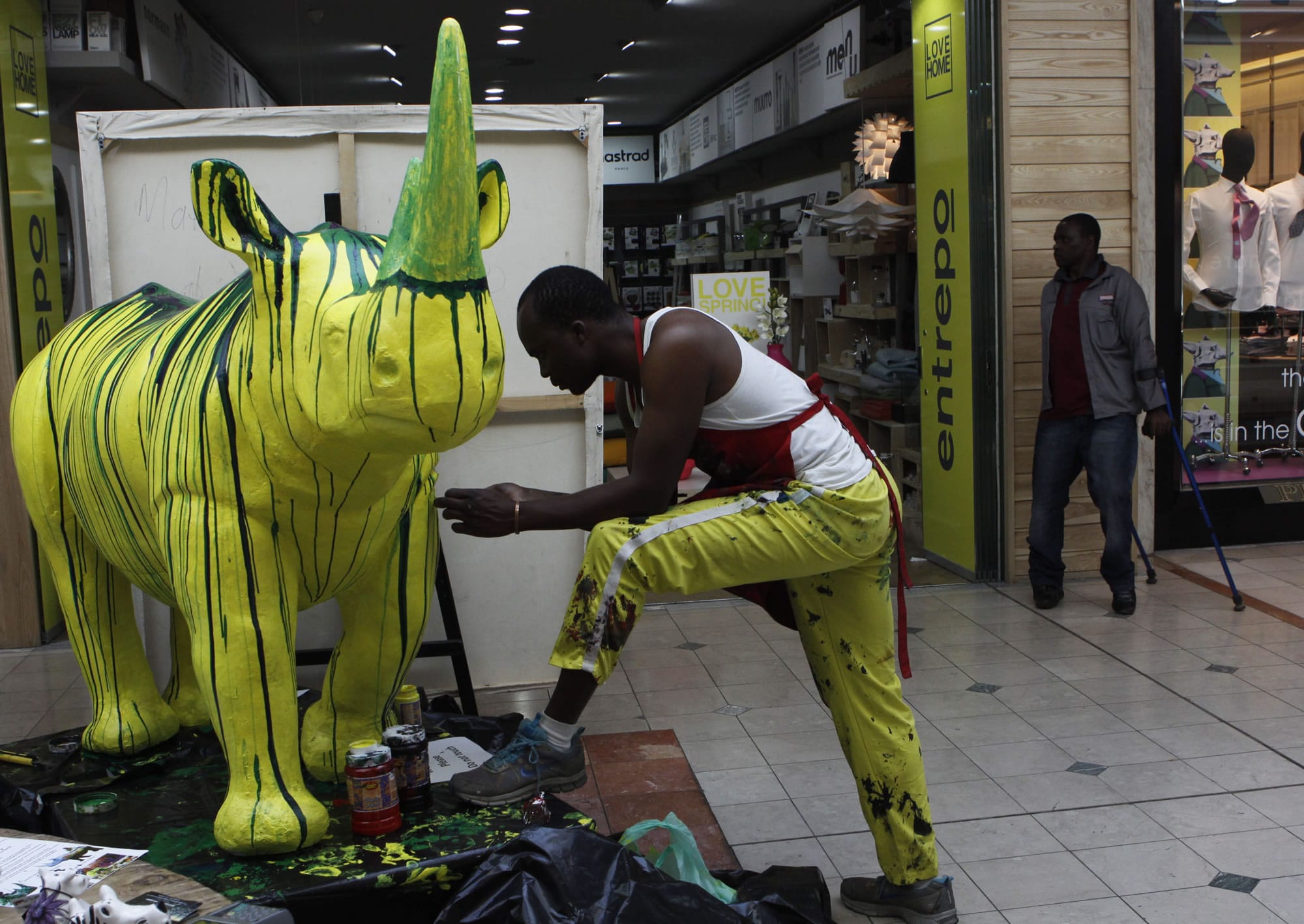 Zimbabwean artist Mathias Chirombo, who works in South Africa, paints a sculpture of a rhino at the Hyde Park shopping center in Johannesburg on Tuesday. Chirombo and three other artists will have their works auctioned by &quot;My Rhino&quot; next month to raise funds in the fight against rhino poaching in the country which will exceed 800 according to government figures.