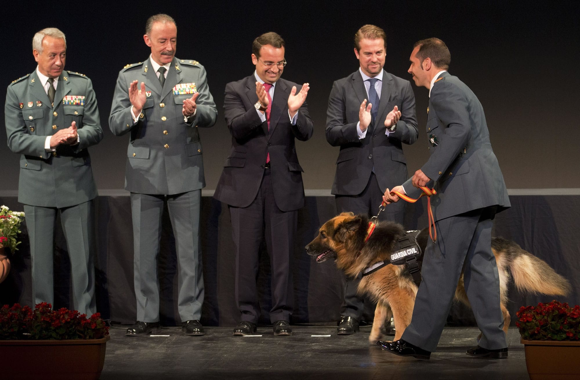 Police dog Ajax is applauded by civil guards and officials as he walks with his handler, Sgt.