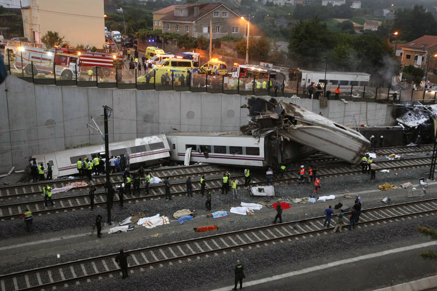 Emergency personnel respond to the scene of a train derailment in Santiago de Compostela, Spain, on Wednesday. A train derailed in northwestern Spain on Wednesday night, toppling passenger cars on their sides and leaving at least one torn open as smoke rose into the air.