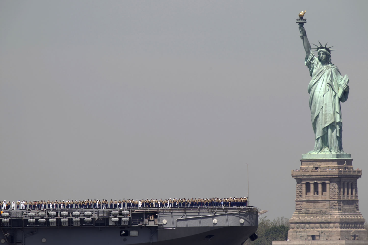 Sailors stand on deck of the USS Iwo Jima as it passes Liberty Island and the Statue of Liberty during 2011 Fleet Week in New York.