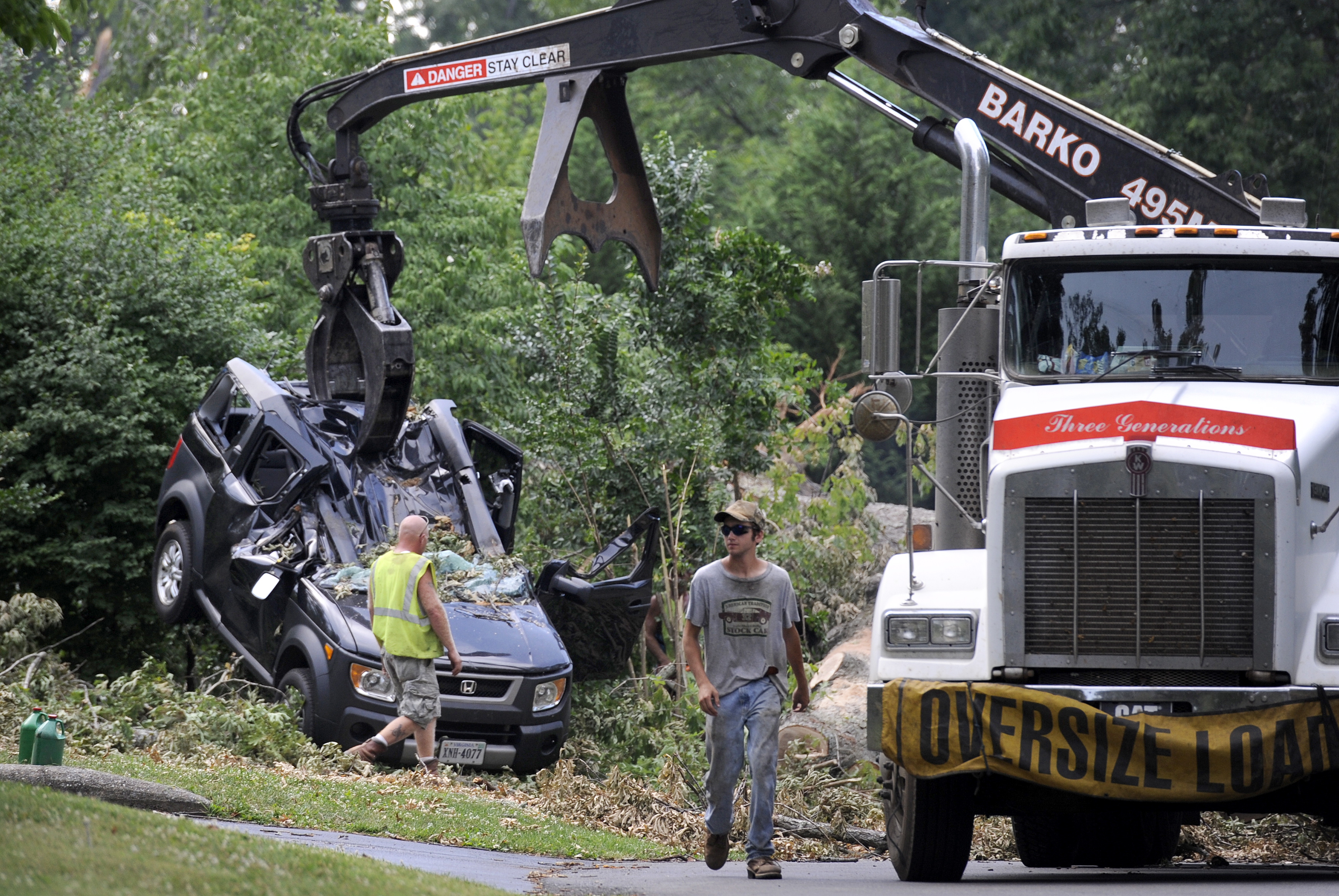 In the process of cutting up and removing an oak tree blocking Inglewood Road on Wednesday in Lynchburg, Va., a crane lifts the crushed Honda Element that Amy Scott and her son, Cooper, were inside of Friday night as the tree fell on top of them.