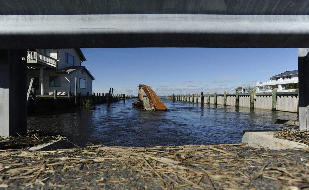 A barge with a piling driver rests on its side at the bottom of a canal on Chincoteague Island, Va. on Wednesday, Oct. 31.