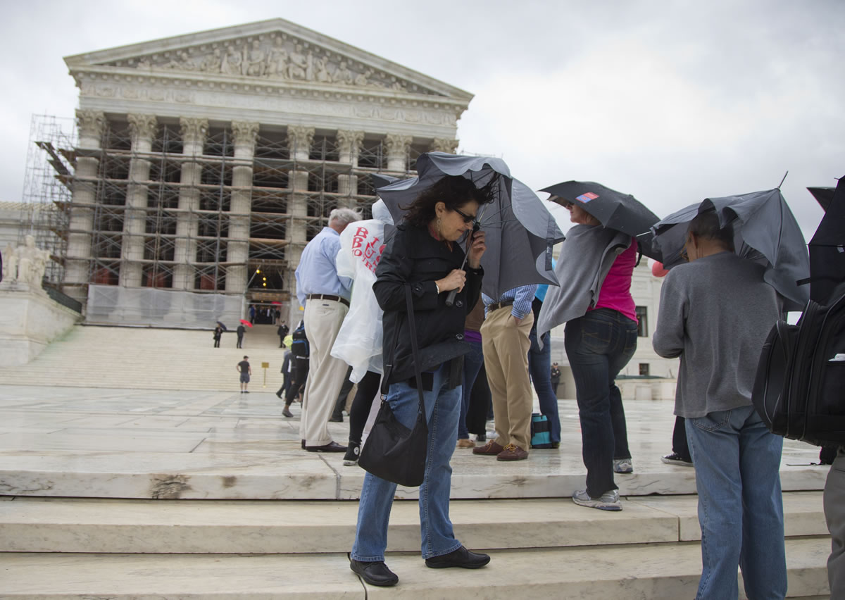 Cynthia Grossman of Lewisville, Colo., holds her umbrella against wind and rain Monday outside the Supreme Court in Washington, D.C., on the first day of the 2013-14 term. The justices took the bench Monday for the start of their new term with important cases about campaign contributions, housing discrimination and government-sanctioned prayer already on tap.