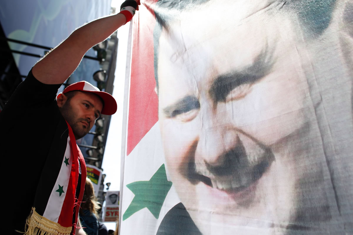 Mahmoud Salameh, of the Queens borough of New York, holds a banner bearing the image of Syrian President Bashar Assad as protesters voice their opposition to the possibility of U.S. military intervention in Syria during a rally Saturday in New York's Times Square. President Barack Obama has called on Congress to approve the use of military force in the wake of a deadly chemical weapons attack his administration blames on the Syrian government.