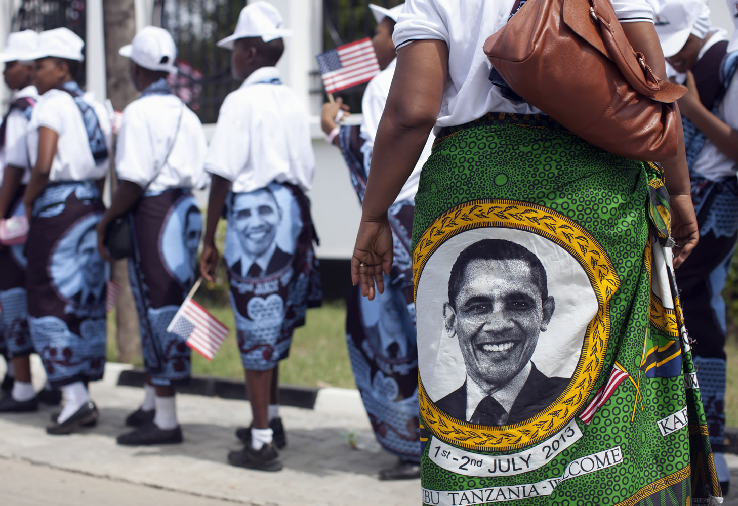 Young girls and women wear khangas, a traditional wrap, with the image of U.S. President Barack Obama as they line up to enter the State House in Dar es Salaam, Tanzania, on Monday to greet and perform for U.S.