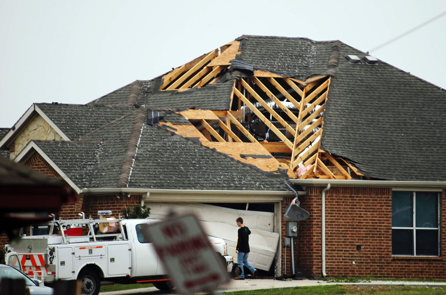 A man walks in front of a home damaged by Wednesday's tornado in Cleburne, Texas. Ten tornadoes touched down in several small communities in Texas overnight, leaving at least six people dead, dozens injured and hundreds homeless.