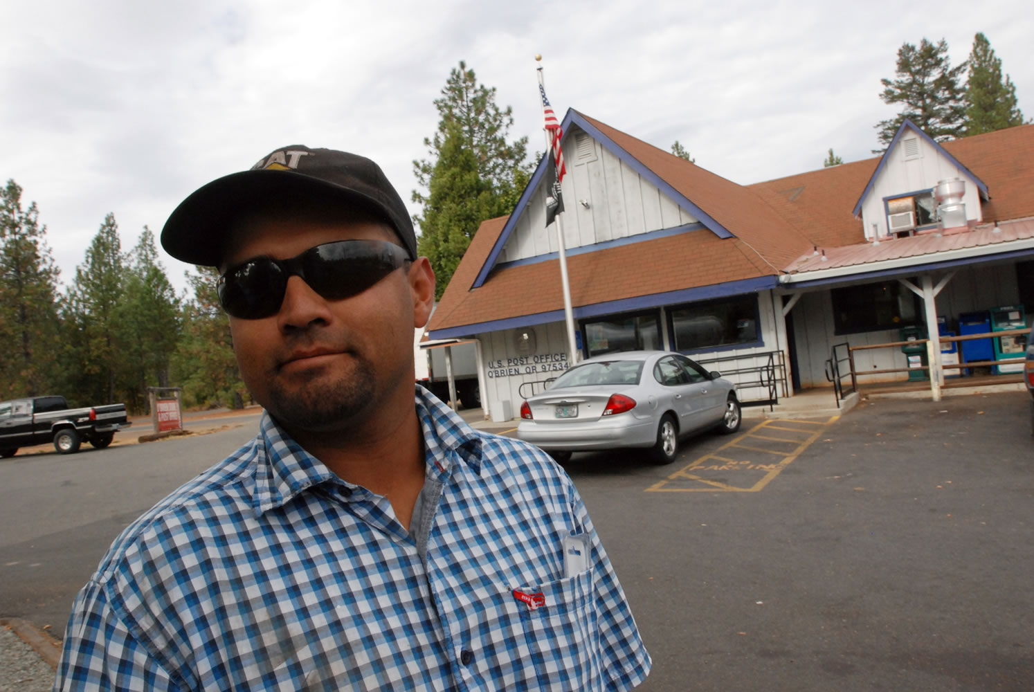In this Oct. 12, 2012, photo, Hector Guzman poses for a photo in front of the post office in O'Brien, Ore., where cuts to sheriff's patrols prompted by the failure of a tax levy have inspired some local residents to organize armed patrols of the rural area of about 750 residents. Guzman, whose home was burglarized several years ago, said he likes the idea of people watching out for each other.