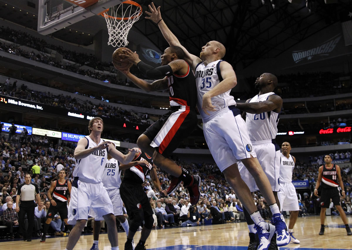 Portland Trail Blazers' Damian Lillard, center, goes up for a shot as Dallas Mavericks' Vince Carter (25) defends during the first half Monday.